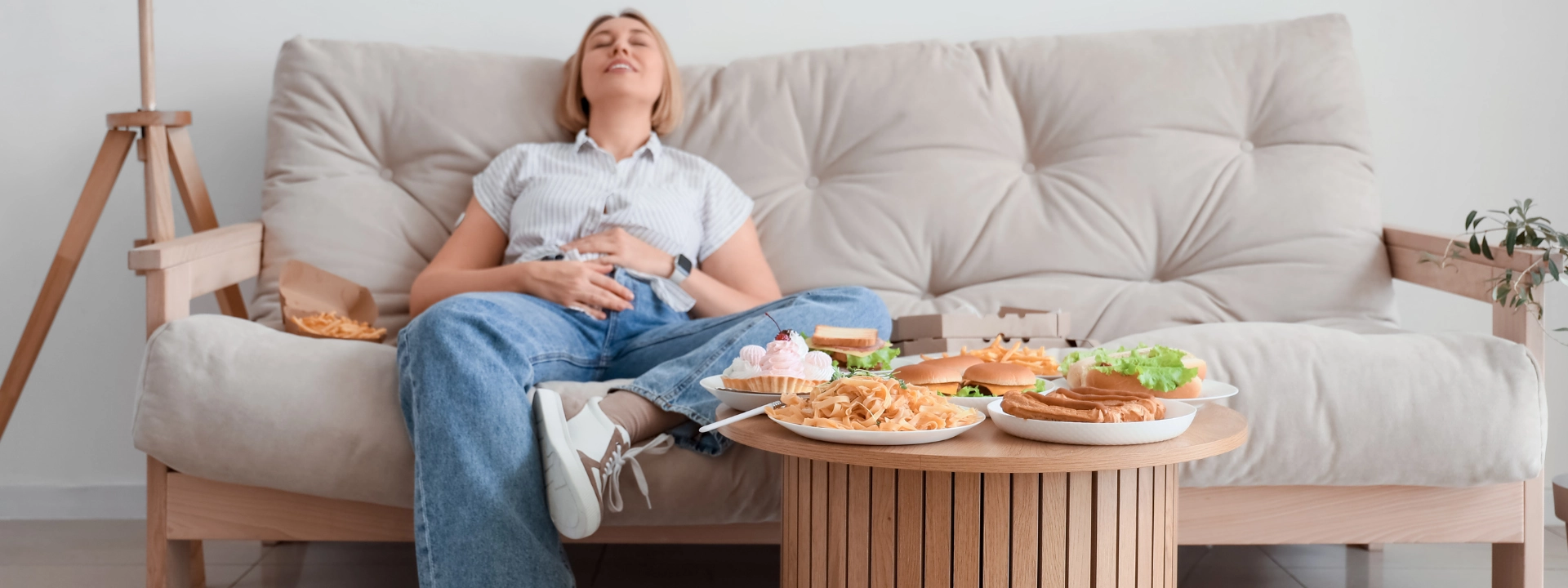 Young woman experiencing discomfort after binge eating fast food and sweets – treatment options for binge eating disorder at Alter Behavioral Health.