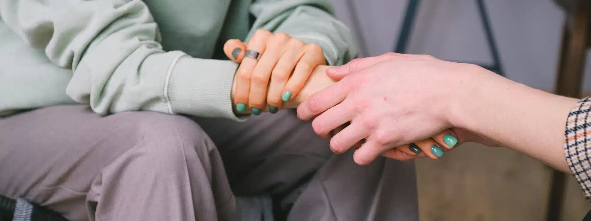 Close-up of two people holding hands in support during therapy – exploring autism diagnosis and emotional responses in mental health care.