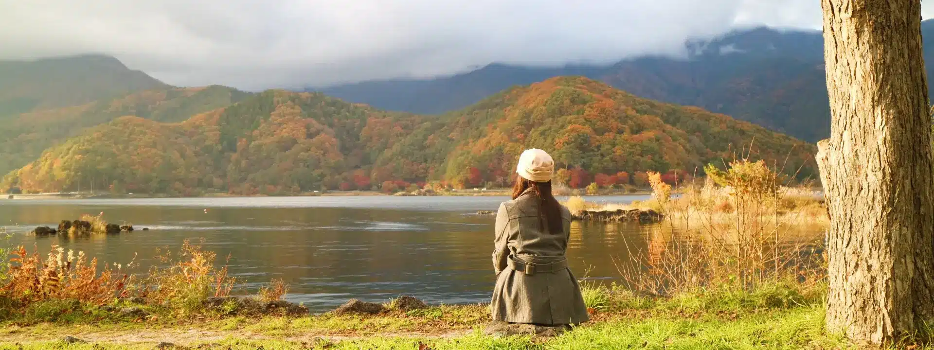 Woman sitting alone by a peaceful lake in autumn – reflecting emotional isolation and internal struggle often experienced with quiet borderline personality disorder (BPD).