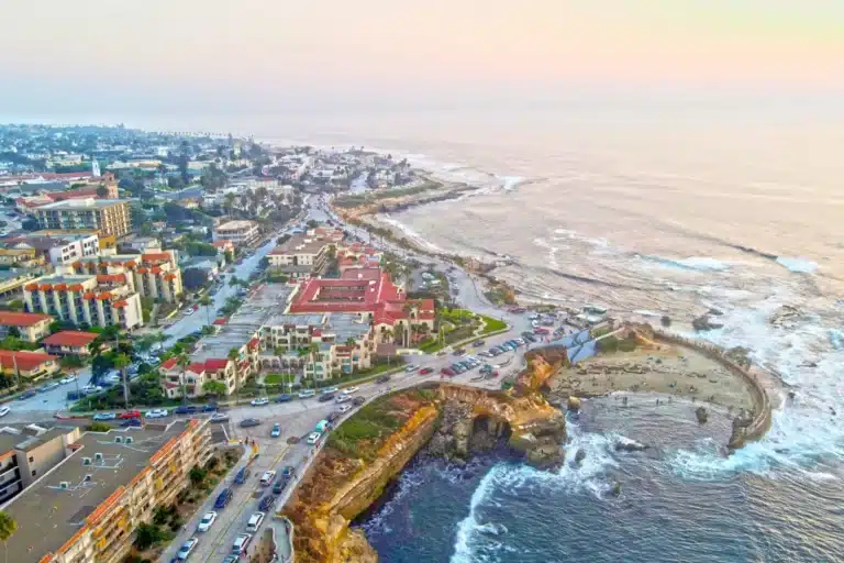 Coastal view of La Jolla, California with rugged cliffs, blue ocean waves, and bright sky showcasing the scenic seaside landscape.