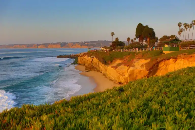 Coastal view of La Jolla, California with rugged cliffs, blue ocean waves, and bright sky showcasing the scenic seaside landscape.