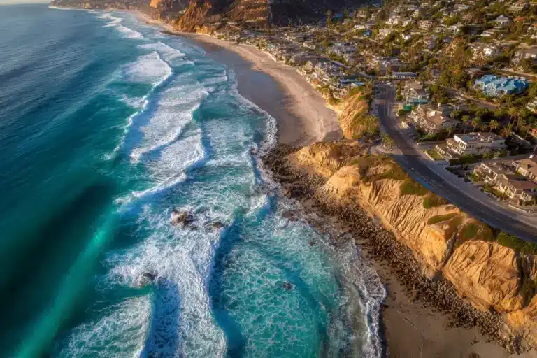 Aerial view of Solana Beach coastline with waves crashing against cliffs and coastal homes overlooking the Pacific Ocean