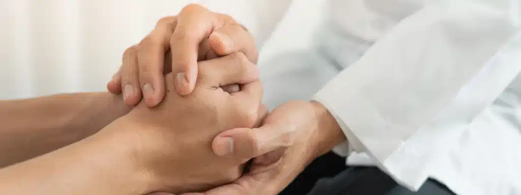 Doctor holding patient’s hands in support during a partial hospitalization program session in California.