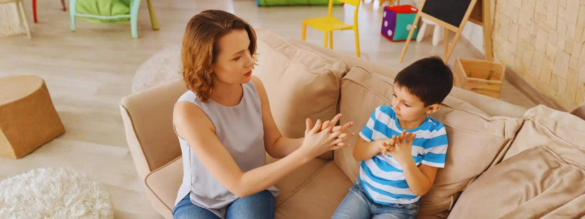 Therapist teaching a young boy with autism using hand exercises during a behavioral therapy session.