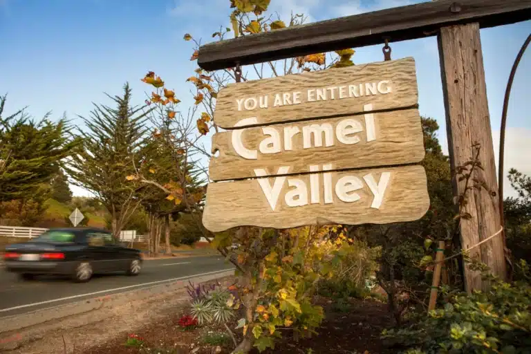 Welcome sign entering Carmel Valley, California surrounded by trees and fall foliage.
