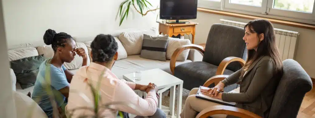 A woman engages in conversation with two individuals in a cozy living room setting.