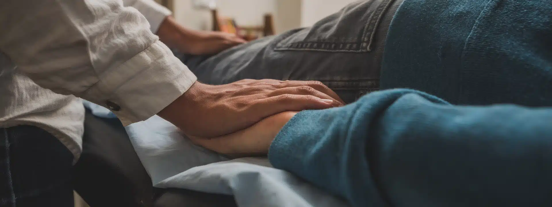 A person gently holds the hand of another, symbolizing support and connection between them.