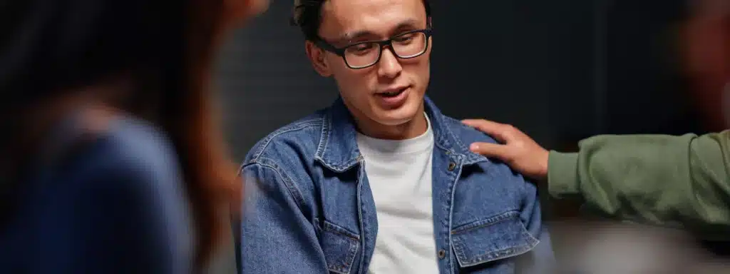 A man wearing glasses engages in conversation with another man, both appearing attentive and focused.
