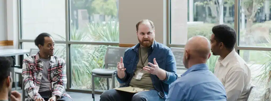 A group of men engaged in conversation while sitting in a circle, fostering discussion and collaboration.