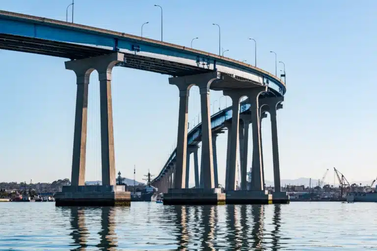 A bridge spans over a calm body of water, reflecting the surrounding landscape in its surface.