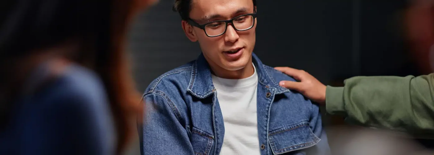 A man wearing glasses engages in conversation with another man, both appearing attentive and focused.