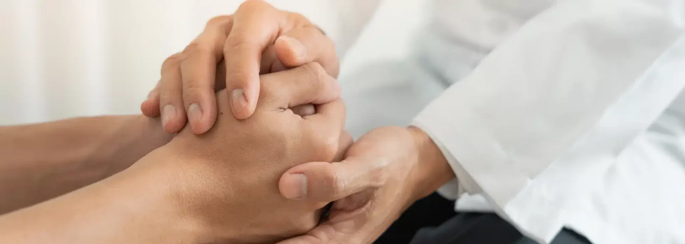 Doctor holding patient’s hands in support during a partial hospitalization program session in California.