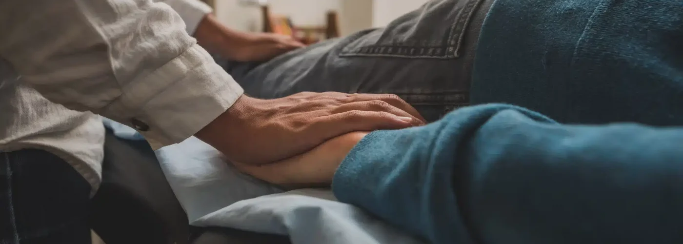 A person gently holds the hand of another, symbolizing support and connection between them.