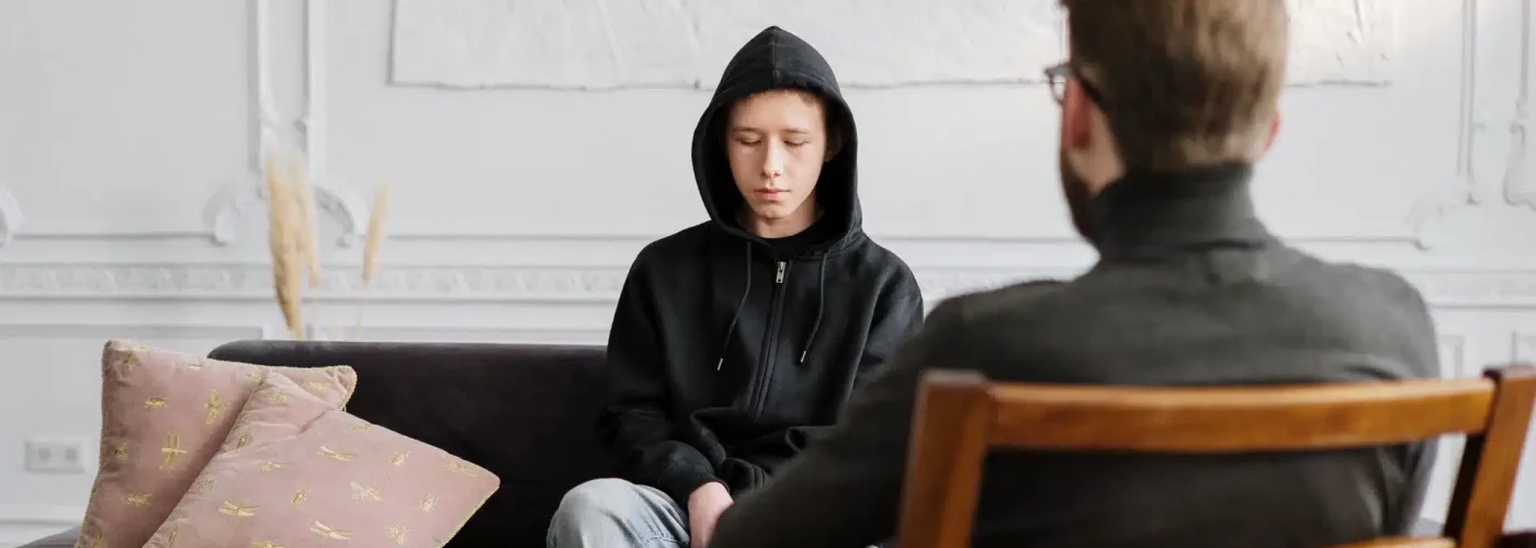 Person wearing a hoodie sitting across from a therapist during a counseling session at a crisis stabilization unit.
