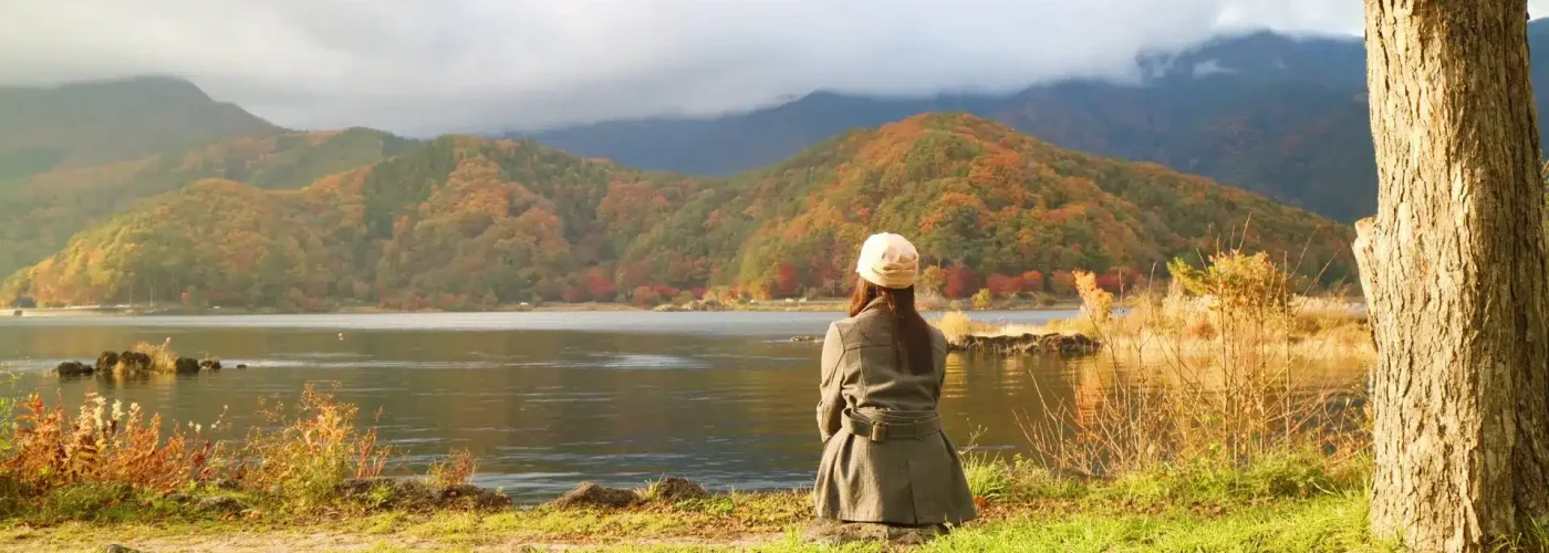 Woman sitting alone by a peaceful lake in autumn – reflecting emotional isolation and internal struggle often experienced with quiet borderline personality disorder (BPD).